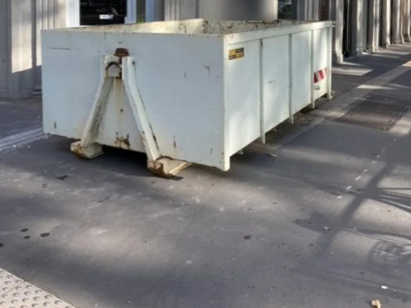 Benne blanche de 10 m³ posée sur le trottoir d'une rue